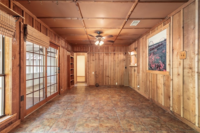 empty room with ceiling fan and wooden walls