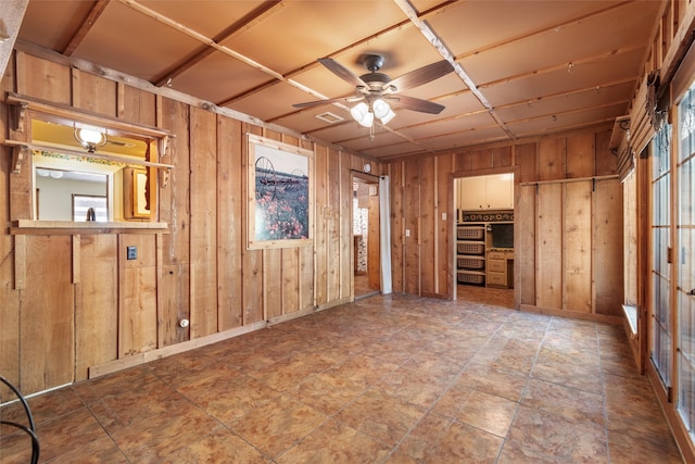 unfurnished room featuring wooden walls and ceiling fan