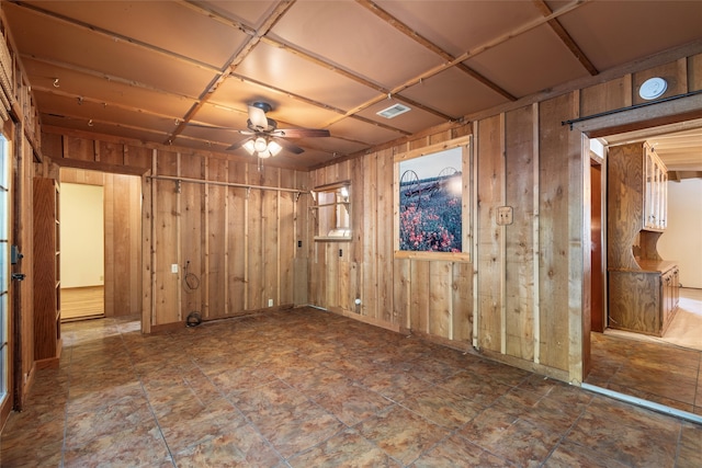 unfurnished room with coffered ceiling, wood walls, and ceiling fan