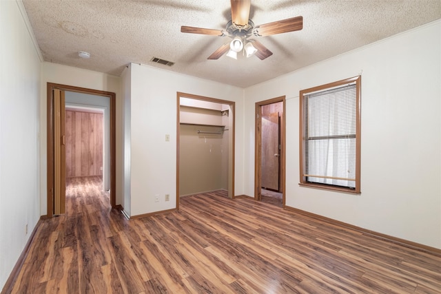 unfurnished bedroom featuring ceiling fan, a textured ceiling, crown molding, and dark wood-type flooring