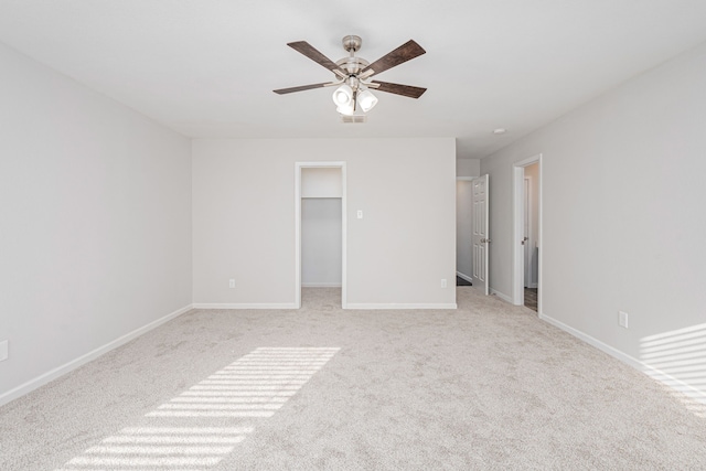 unfurnished bedroom with ceiling fan, light colored carpet, a closet, and a walk in closet