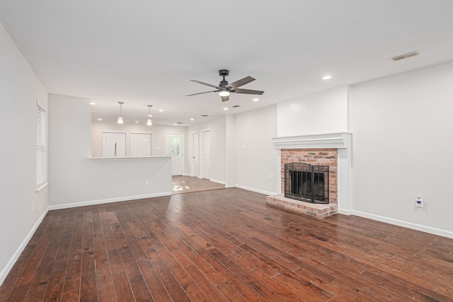 unfurnished living room featuring a brick fireplace, ceiling fan, and dark wood-type flooring