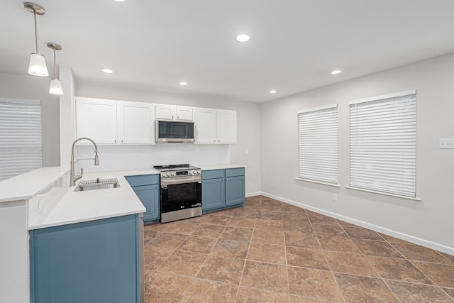 kitchen with pendant lighting, sink, white cabinetry, blue cabinetry, and appliances with stainless steel finishes