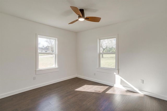 empty room with a wealth of natural light, ceiling fan, and dark wood-type flooring