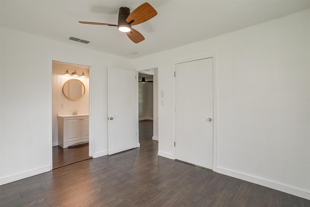 unfurnished bedroom featuring ensuite bath, ceiling fan, dark wood-type flooring, and sink