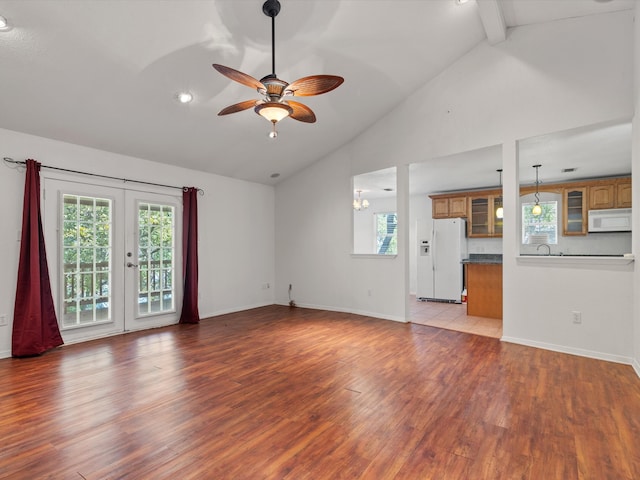 unfurnished living room with beam ceiling, ceiling fan, french doors, and light wood-type flooring