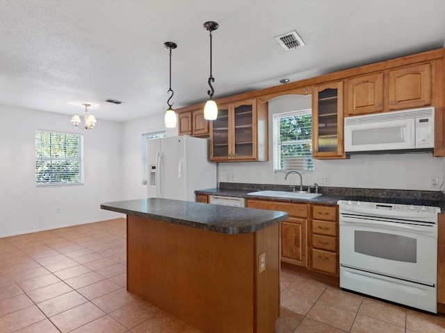 kitchen with white appliances, decorative light fixtures, a wealth of natural light, and sink