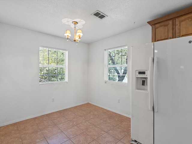 interior space with a notable chandelier, light tile patterned flooring, and a textured ceiling