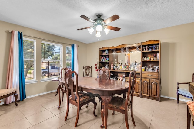 dining room with ceiling fan, light tile patterned flooring, a textured ceiling, and indoor bar