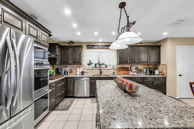 kitchen featuring decorative backsplash, light tile patterned floors, stainless steel appliances, a center island, and sink