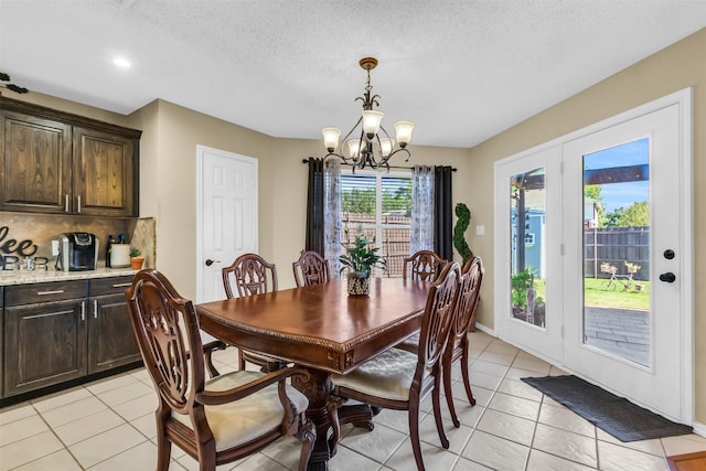 dining space with a textured ceiling, light tile patterned flooring, and an inviting chandelier