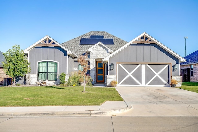 view of front of home with a garage, central AC, and a front lawn