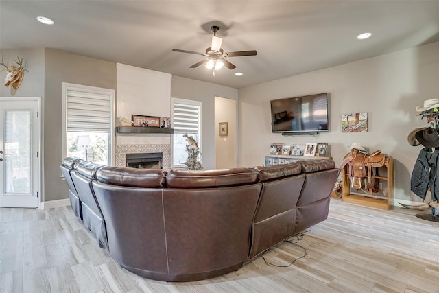 living room featuring ceiling fan, a fireplace, and light hardwood / wood-style flooring