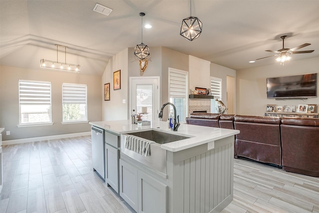 kitchen with light hardwood / wood-style floors, dishwasher, decorative light fixtures, a center island with sink, and sink