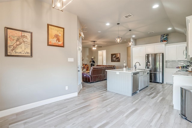 kitchen with pendant lighting, white cabinets, a kitchen island with sink, appliances with stainless steel finishes, and light hardwood / wood-style floors