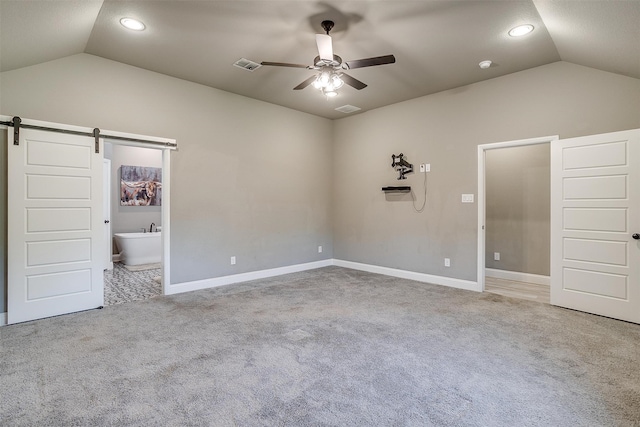 unfurnished bedroom with vaulted ceiling, ceiling fan, light colored carpet, and a barn door