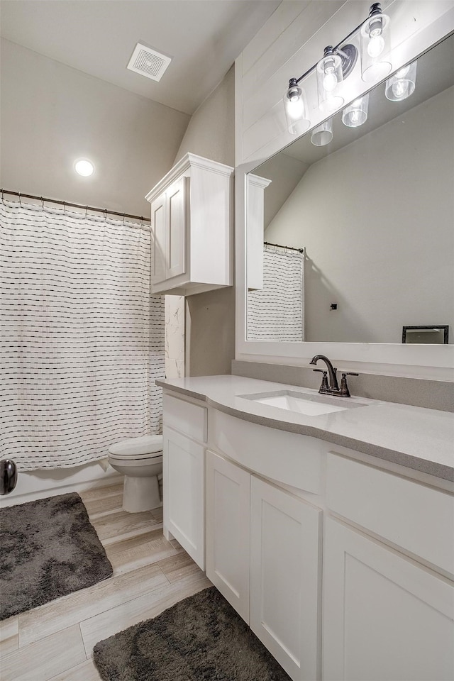 full bathroom with wood-type flooring, shower / tub combo with curtain, vanity, and toilet