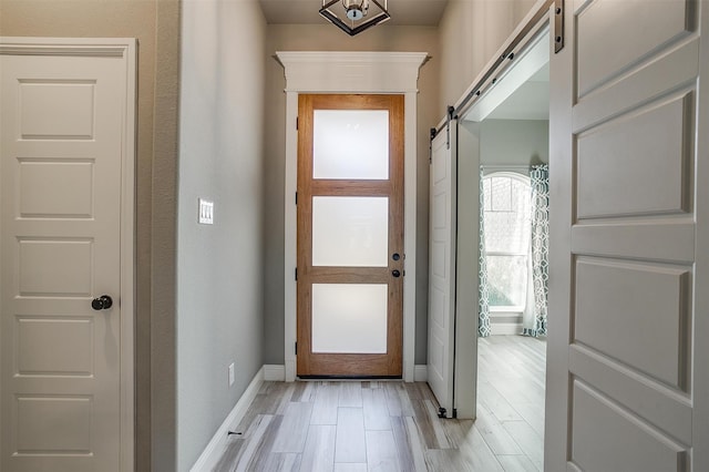 doorway to outside with light wood-type flooring and a barn door