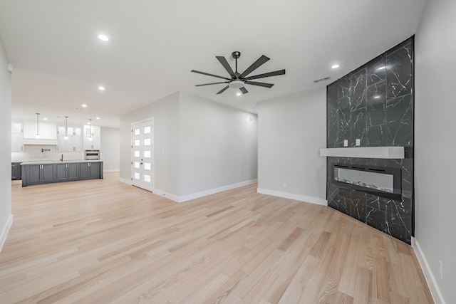 unfurnished living room with light hardwood / wood-style floors, a high end fireplace, and ceiling fan