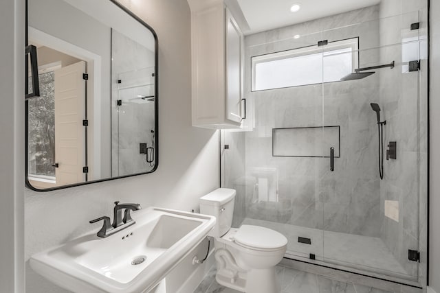 bathroom with toilet, sink, and a shower with shower door