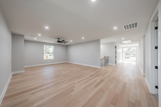 empty room featuring a skylight, light hardwood / wood-style floors, and ceiling fan