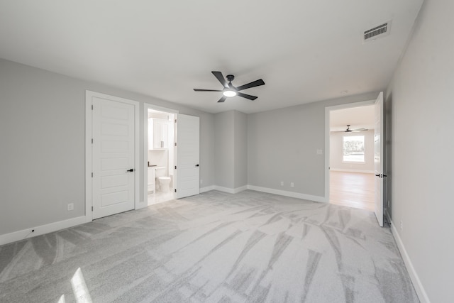 unfurnished bedroom featuring light carpet, ensuite bathroom, and ceiling fan