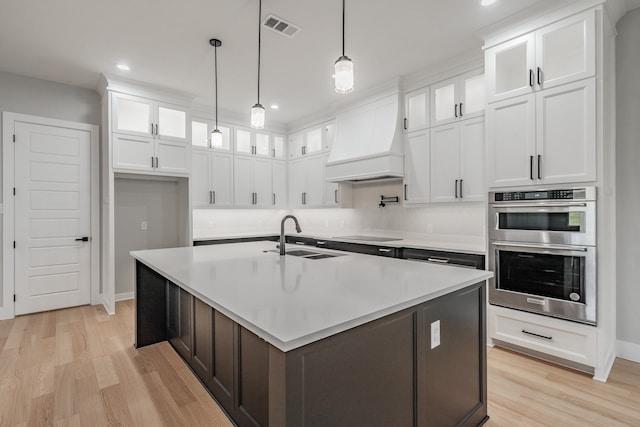 kitchen with an island with sink and white cabinetry