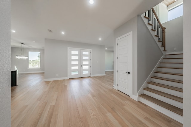 interior space featuring french doors, light hardwood / wood-style flooring, and an inviting chandelier