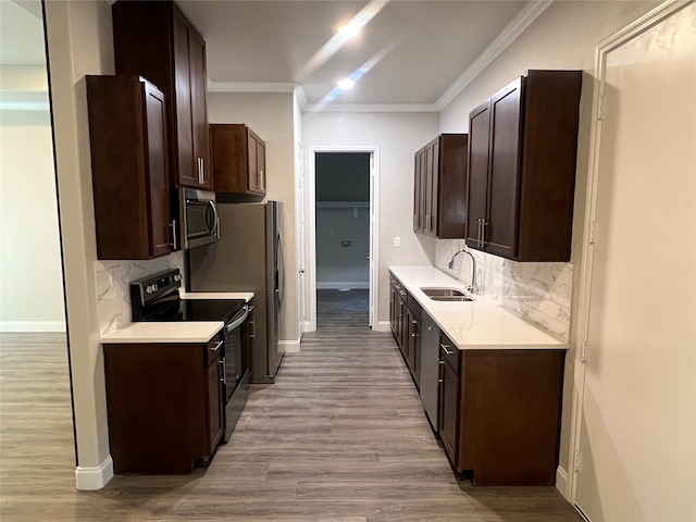 kitchen with light wood-type flooring, ornamental molding, sink, and stainless steel appliances