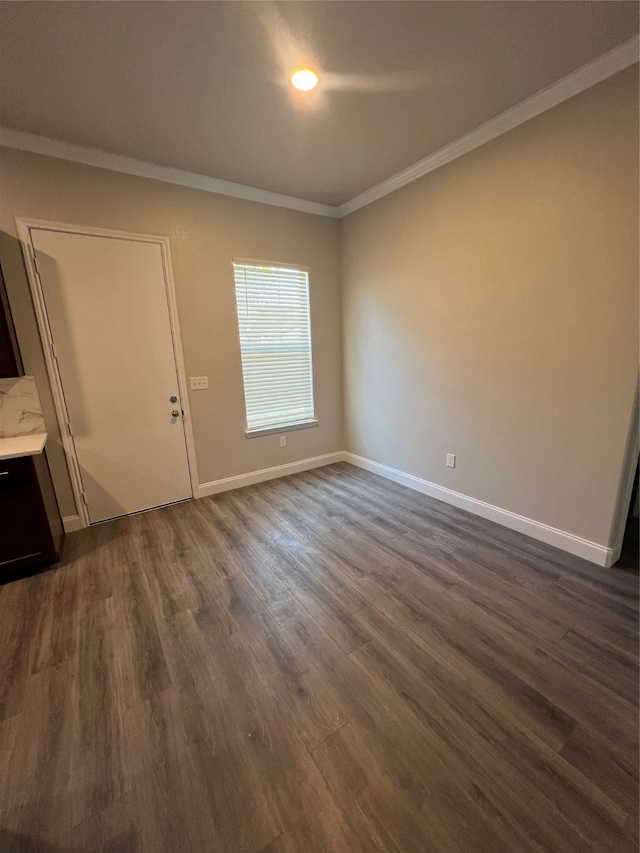 spare room featuring ornamental molding and dark wood-type flooring