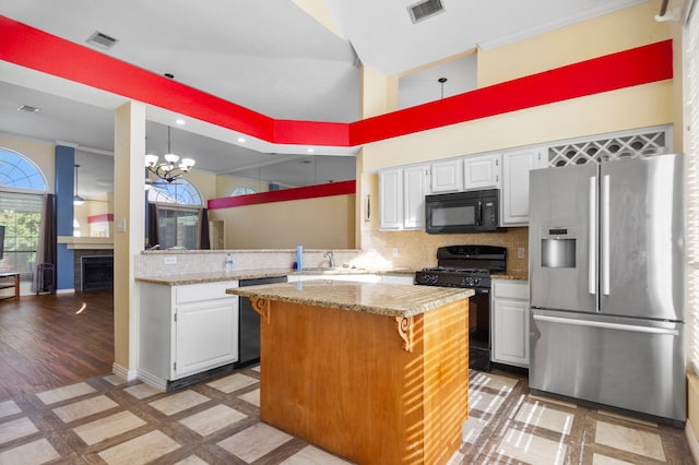 kitchen with tasteful backsplash, white cabinetry, black appliances, a center island, and a towering ceiling