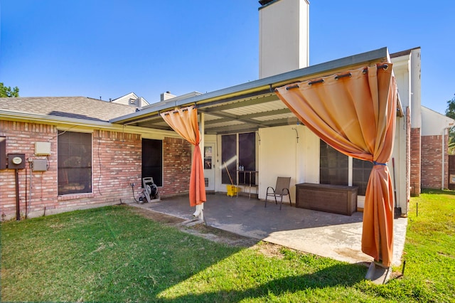 back of property with a lawn and a patio