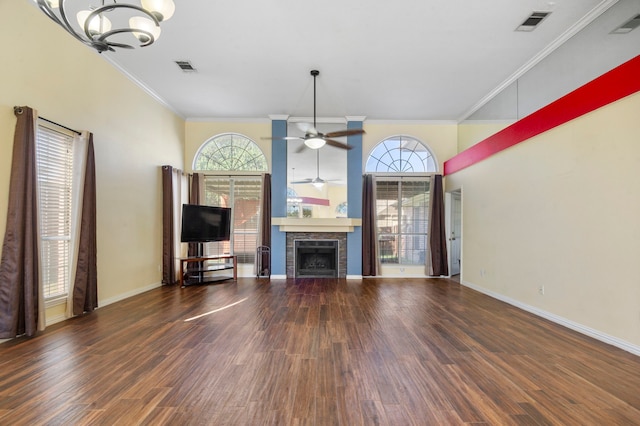 unfurnished living room featuring ornamental molding, ceiling fan with notable chandelier, a fireplace, and dark hardwood / wood-style flooring