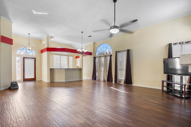 unfurnished living room with ceiling fan with notable chandelier, a towering ceiling, and dark wood-type flooring