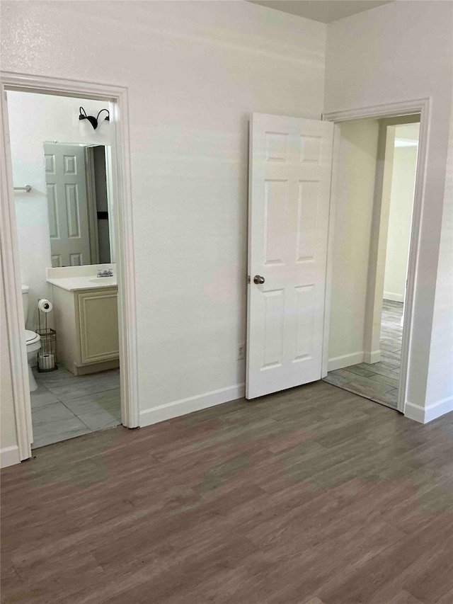 unfurnished bedroom with ensuite bath and hardwood / wood-style flooring