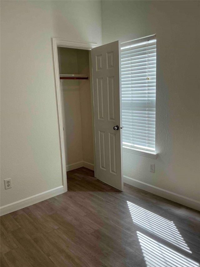 unfurnished bedroom featuring a closet and dark wood-type flooring