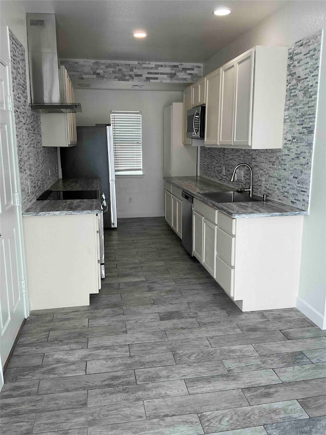 kitchen featuring appliances with stainless steel finishes, decorative backsplash, white cabinetry, sink, and extractor fan