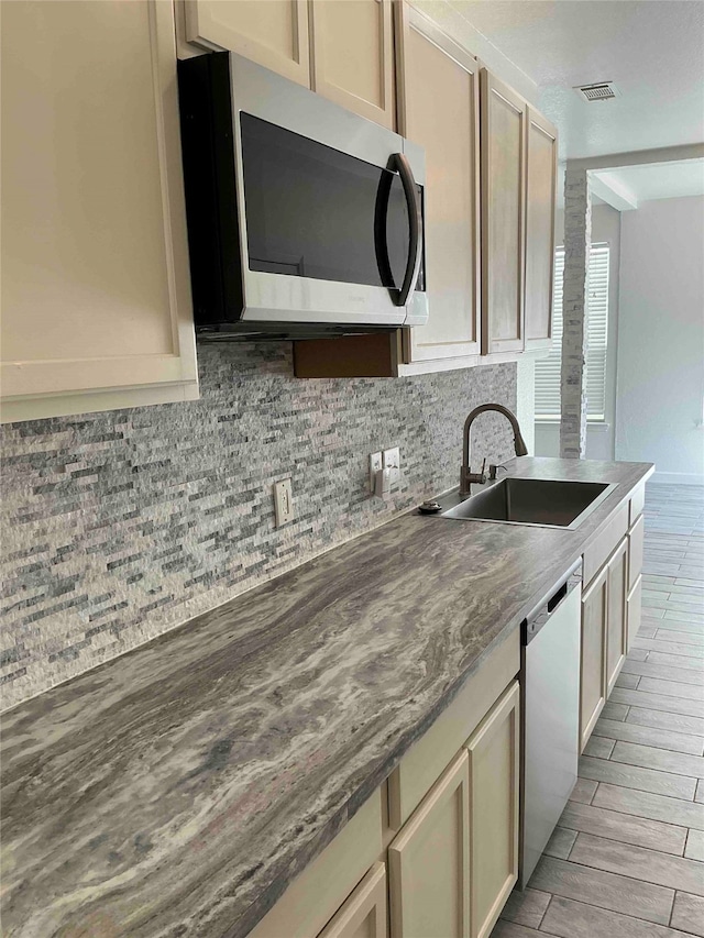 kitchen featuring appliances with stainless steel finishes, light hardwood / wood-style floors, cream cabinets, and sink