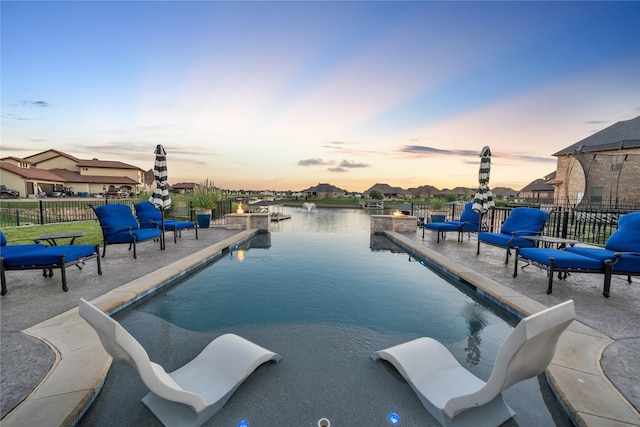 pool at dusk featuring a water view