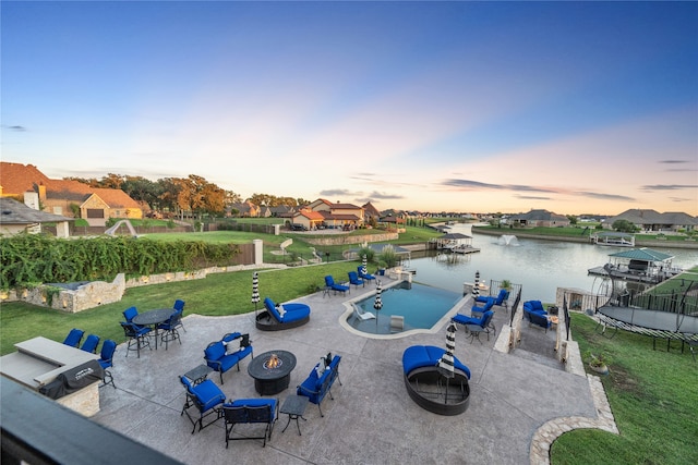 exterior space featuring a lawn, a water view, and an outdoor fire pit