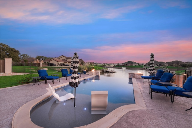 pool at dusk with a patio and a water view