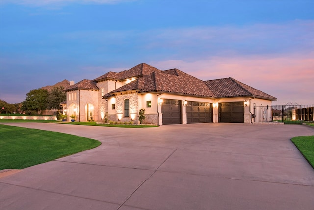 mediterranean / spanish home featuring a garage and a lawn