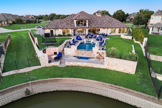 rear view of house featuring a pool with hot tub, a yard, and a patio area