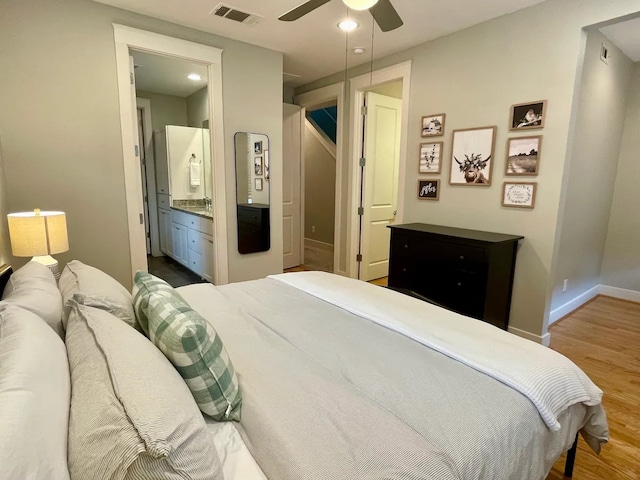 bedroom with hardwood / wood-style floors, ensuite bathroom, and ceiling fan