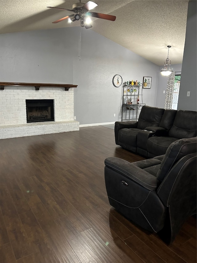 living room with a textured ceiling, vaulted ceiling, a fireplace, dark hardwood / wood-style flooring, and ceiling fan