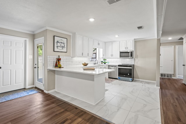 kitchen with white cabinetry, appliances with stainless steel finishes, light hardwood / wood-style flooring, and kitchen peninsula