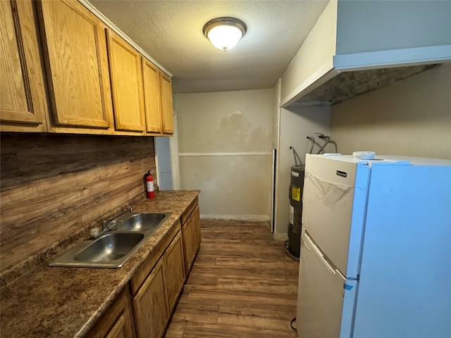 kitchen with white refrigerator, sink, a textured ceiling, water heater, and dark hardwood / wood-style flooring