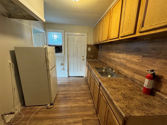 kitchen with sink, white refrigerator, hardwood / wood-style floors, and tasteful backsplash