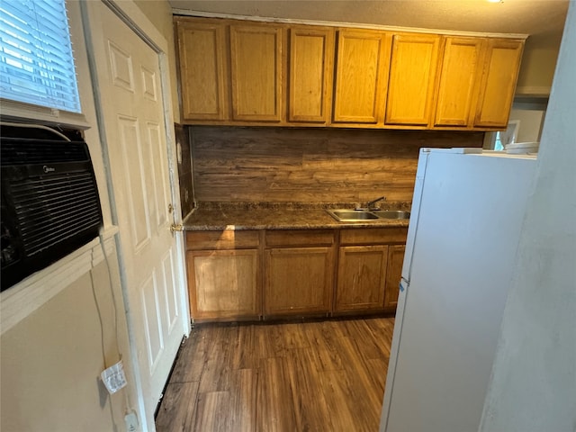 kitchen featuring dark hardwood / wood-style floors, dark stone countertops, white fridge, and sink