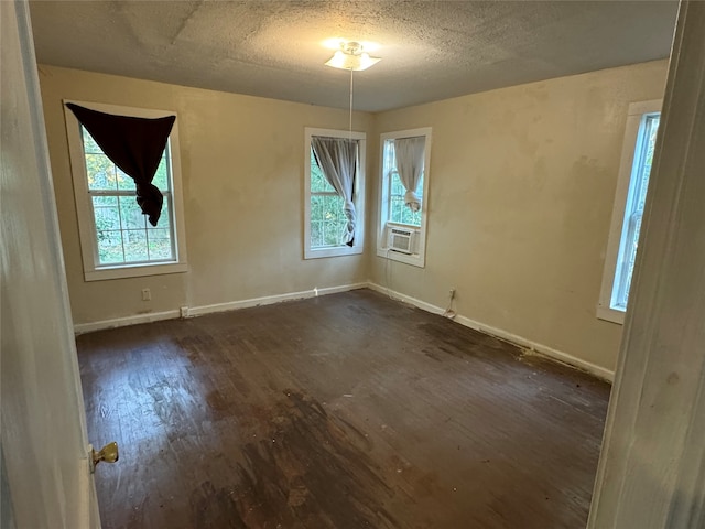 spare room featuring cooling unit, a textured ceiling, and dark hardwood / wood-style floors